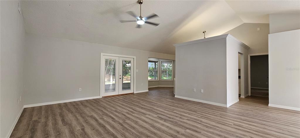 A spacious living room features vaulted ceilings, light gray walls, and wood-look laminate flooring — 370 S COBBLE COURT, MOUNT DORA, FL