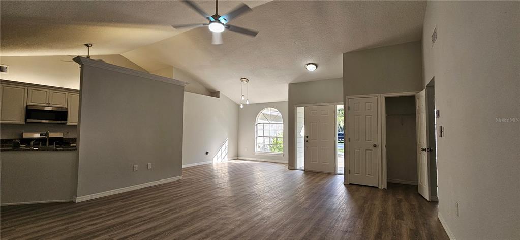 An open-concept living area features vaulted ceilings, light wood-look flooring, and an adjacent kitchen — 370 S COBBLE COURT, MOUNT DORA, FL
