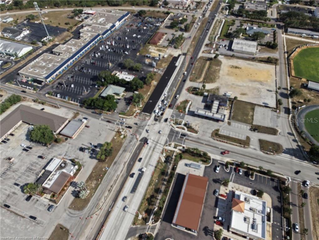 This aerial view shows a commercial intersection with parking lots, roadways, and surrounding buildings — 123 US 27 N, LAKE PLACID, FL