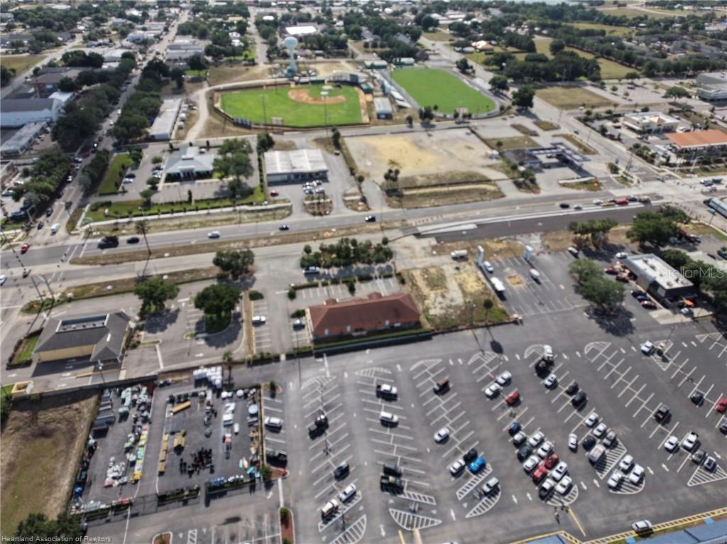 An aerial view shows a commercial parking lot, nearby buildings, and a baseball field — 123 US 27 N, LAKE PLACID, FL