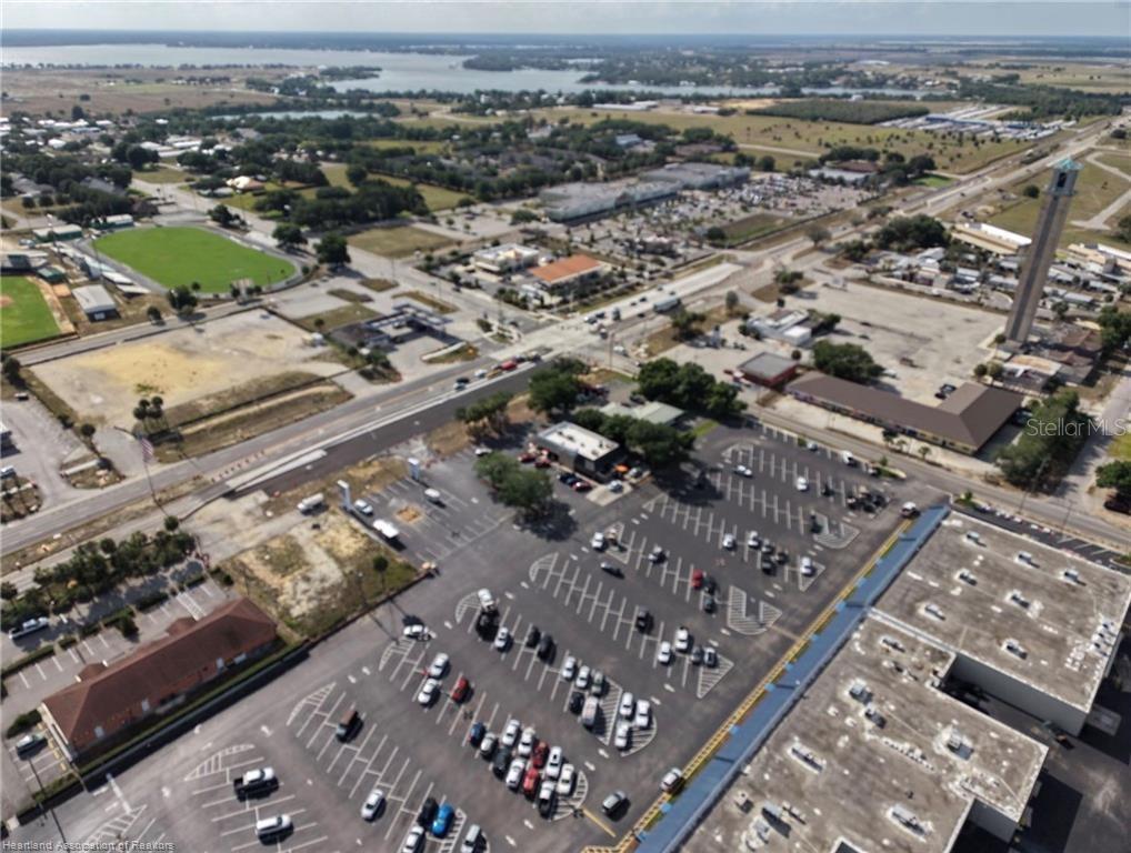An aerial view shows a large parking lot, commercial buildings, and a nearby sports field — 123 US 27 N, LAKE PLACID, FL