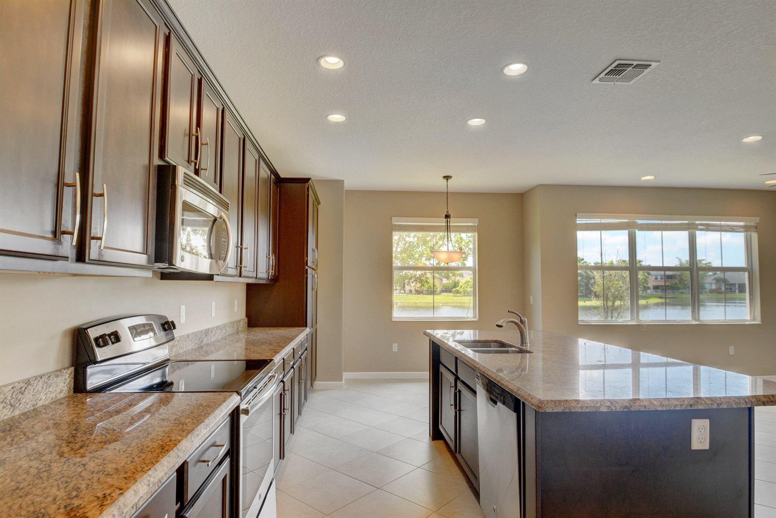 A kitchen with dark wood cabinets, granite countertops, stainless steel appliances, and a center island — 2916 Payson Way, Wellington FL 33414, WELLINGTON, FL