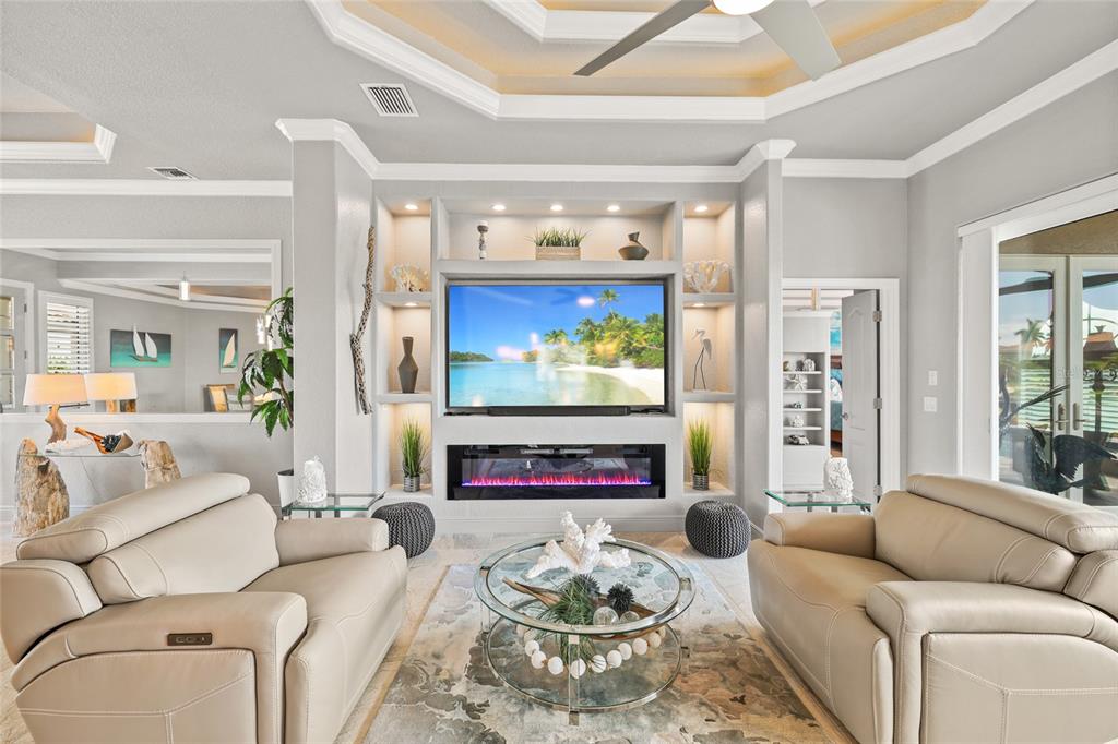 A living room features a built-in media center with a fireplace, two sofas, and decor — 1317 PINE SISKIN DRIVE, PUNTA GORDA, FL
