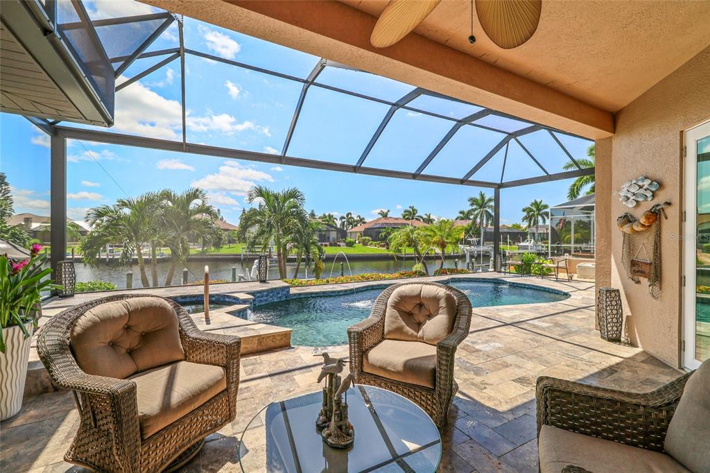 A covered patio features wicker furniture, a pool, and a view of a canal — 1317 PINE SISKIN DRIVE, PUNTA GORDA, FL