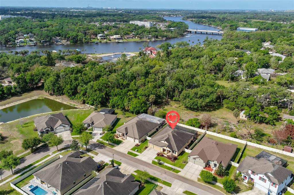 An aerial view shows a suburban neighborhood with houses, a river, and a bridge — 11014 BRAHMAN RANCH CIRCLE, RIVERVIEW, FL