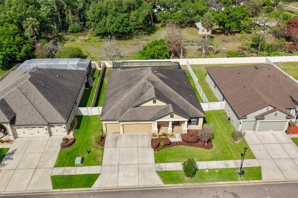 An aerial view shows three suburban houses with driveways, lawns, and fenced backyards — 11014 BRAHMAN RANCH CIRCLE, RIVERVIEW, FL
