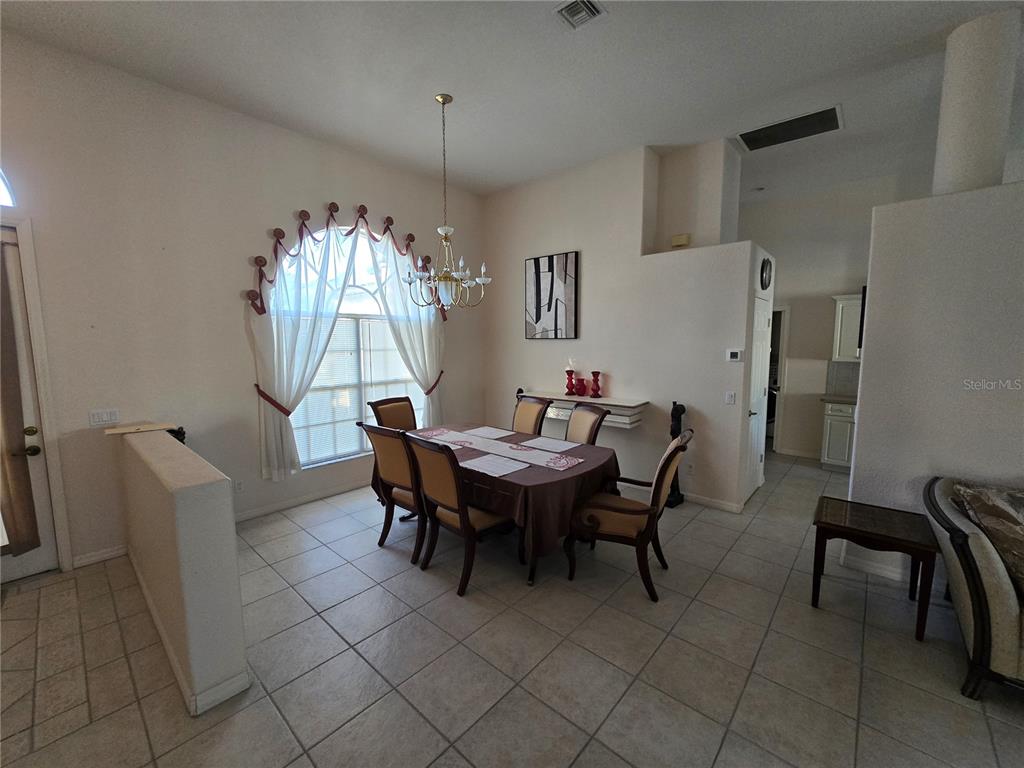 A dining room with tile floors, a chandelier, and a large arched window with curtains — 23404 PEACHLAND BOULEVARD, PORT CHARLOTTE, FL