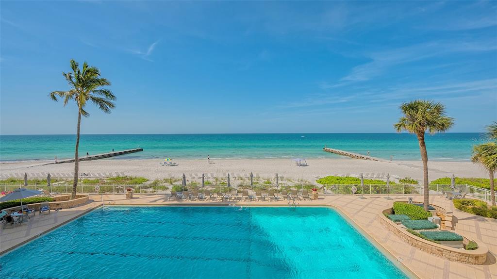 An elevated view of a swimming pool overlooking a sandy beach and the ocean — 2301 GULF OF MEXICO DRIVE UNIT 33N, LONGBOAT KEY, FL