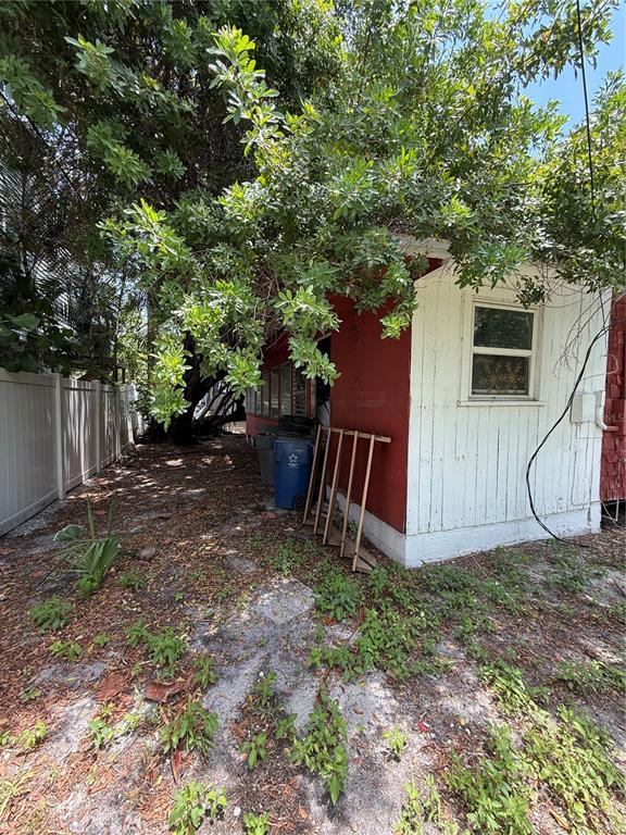 A side view of a small house with white vertical siding and red trim — 116 85TH AVENUE, TREASURE ISLAND, FL