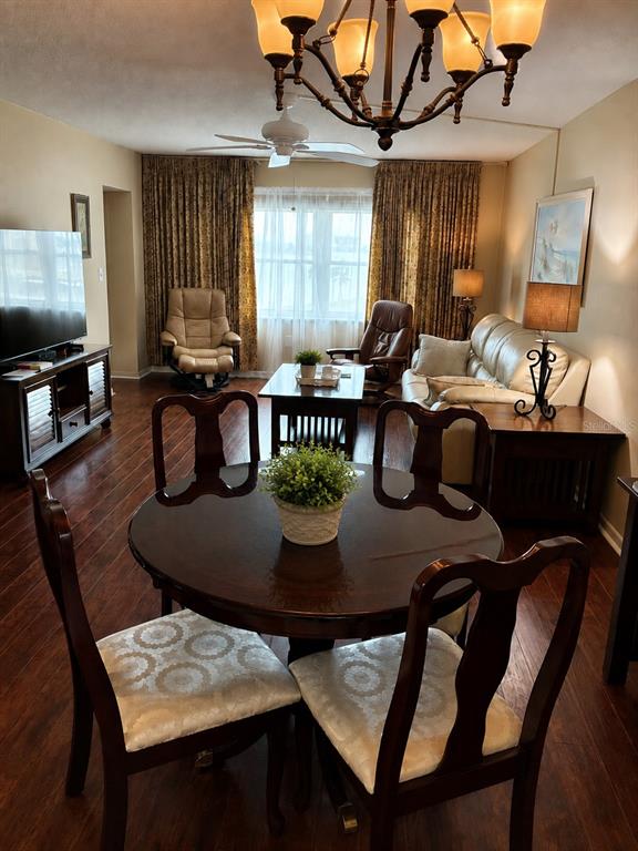 A dining area with a round table and chairs sits before a living room space — 4575 COVE CIRCLE UNIT 506, ST PETERSBURG, FL