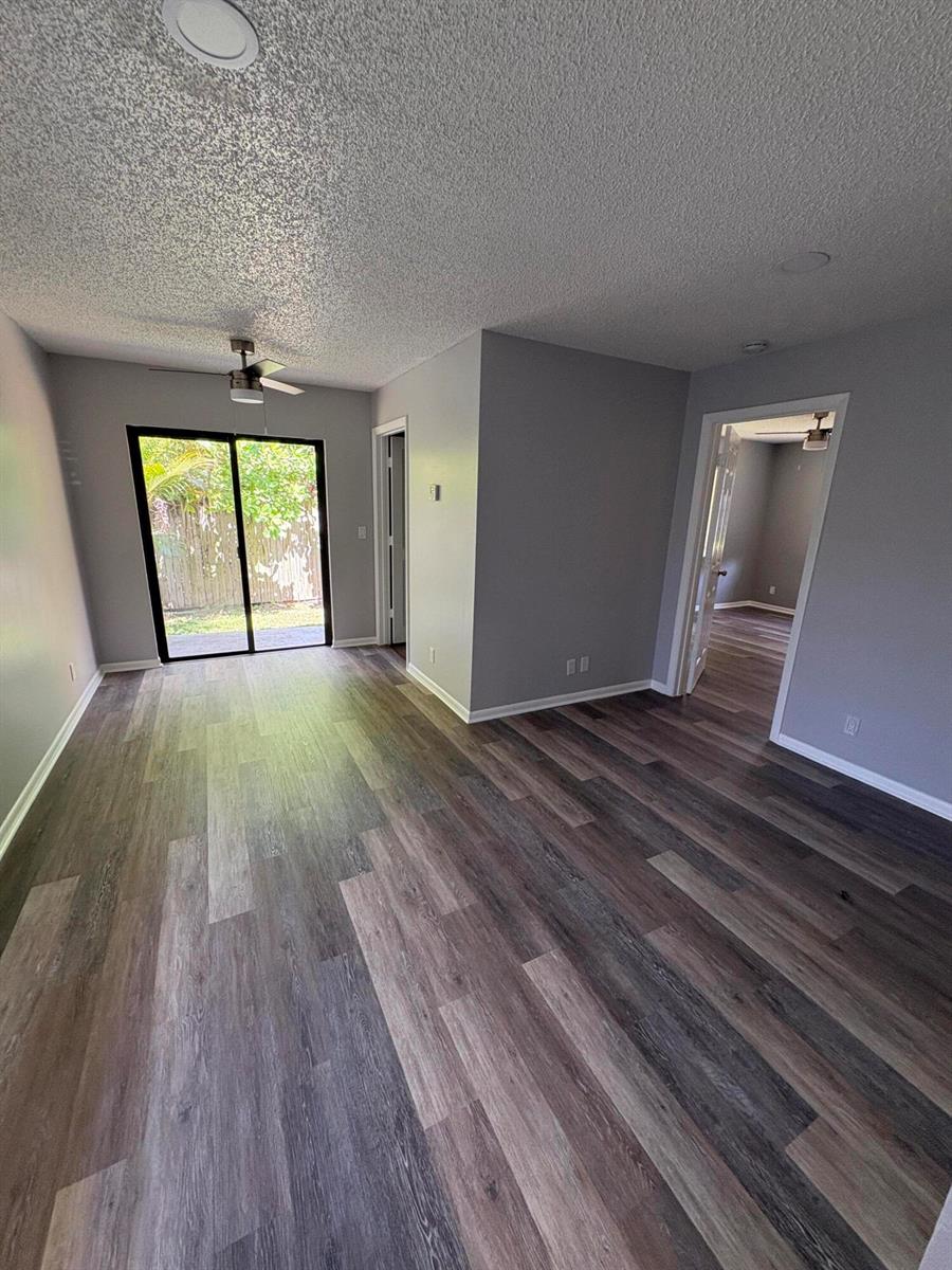 An empty room with gray walls, wood-look flooring, a ceiling fan, and a sliding glass door — 4726 Summit Boulevard, West Palm Beach FL 33415, WEST PALM BEACH, FL