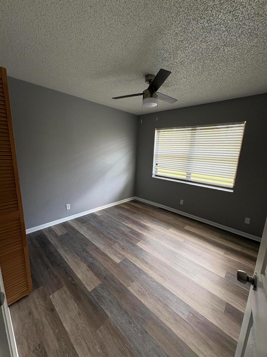 An empty bedroom features gray walls, wood-look plank flooring, and a ceiling fan — 4726 Summit Boulevard, West Palm Beach FL 33415, WEST PALM BEACH, FL