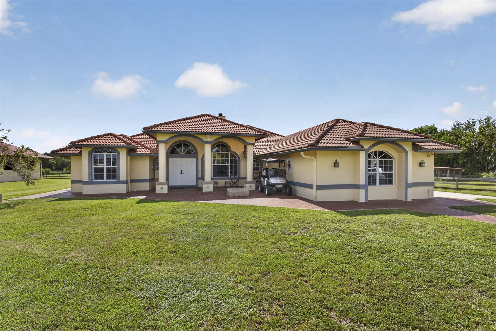 A single-story yellow house with a tiled roof and a golf cart parked outside — 2564 Deer Run Trail, Loxahatchee FL 33470, LOXAHATCHEE, FL