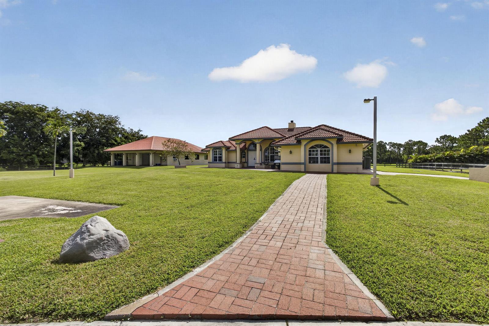 A brick walkway leads to a single-story house with a tile roof and detached garage — 2564 Deer Run Trail, Loxahatchee FL 33470, LOXAHATCHEE, FL