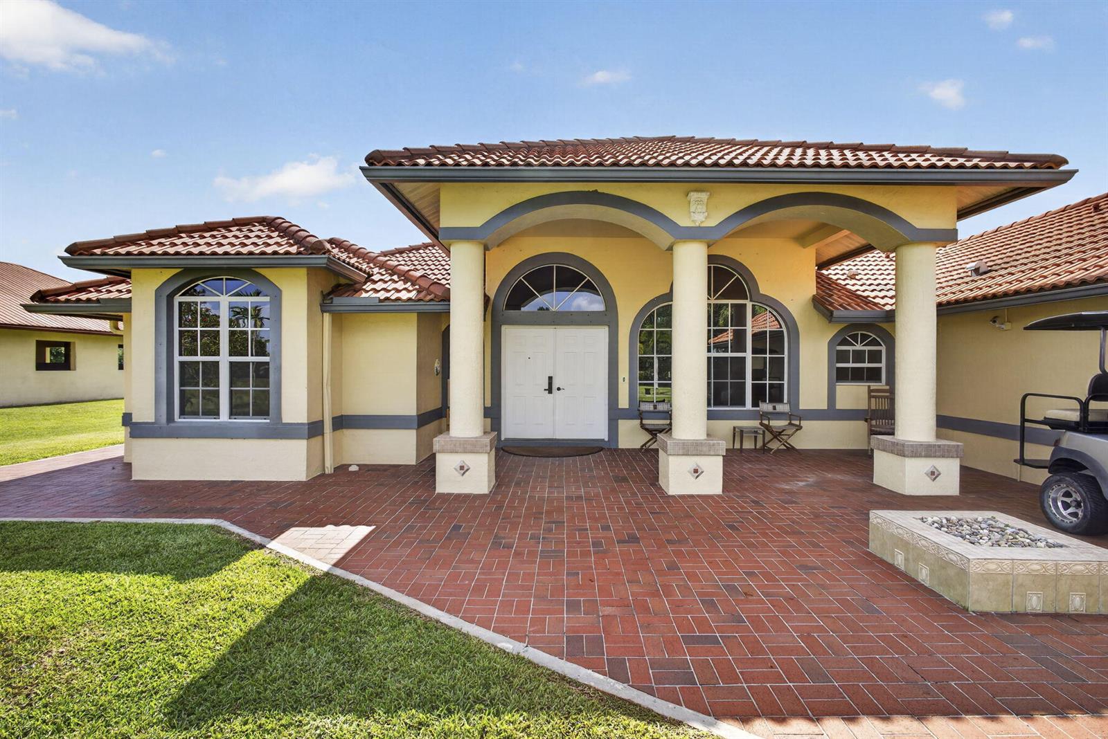 A yellow house with a red tile roof and a brick patio entrance — 2564 Deer Run Trail, Loxahatchee FL 33470, LOXAHATCHEE, FL