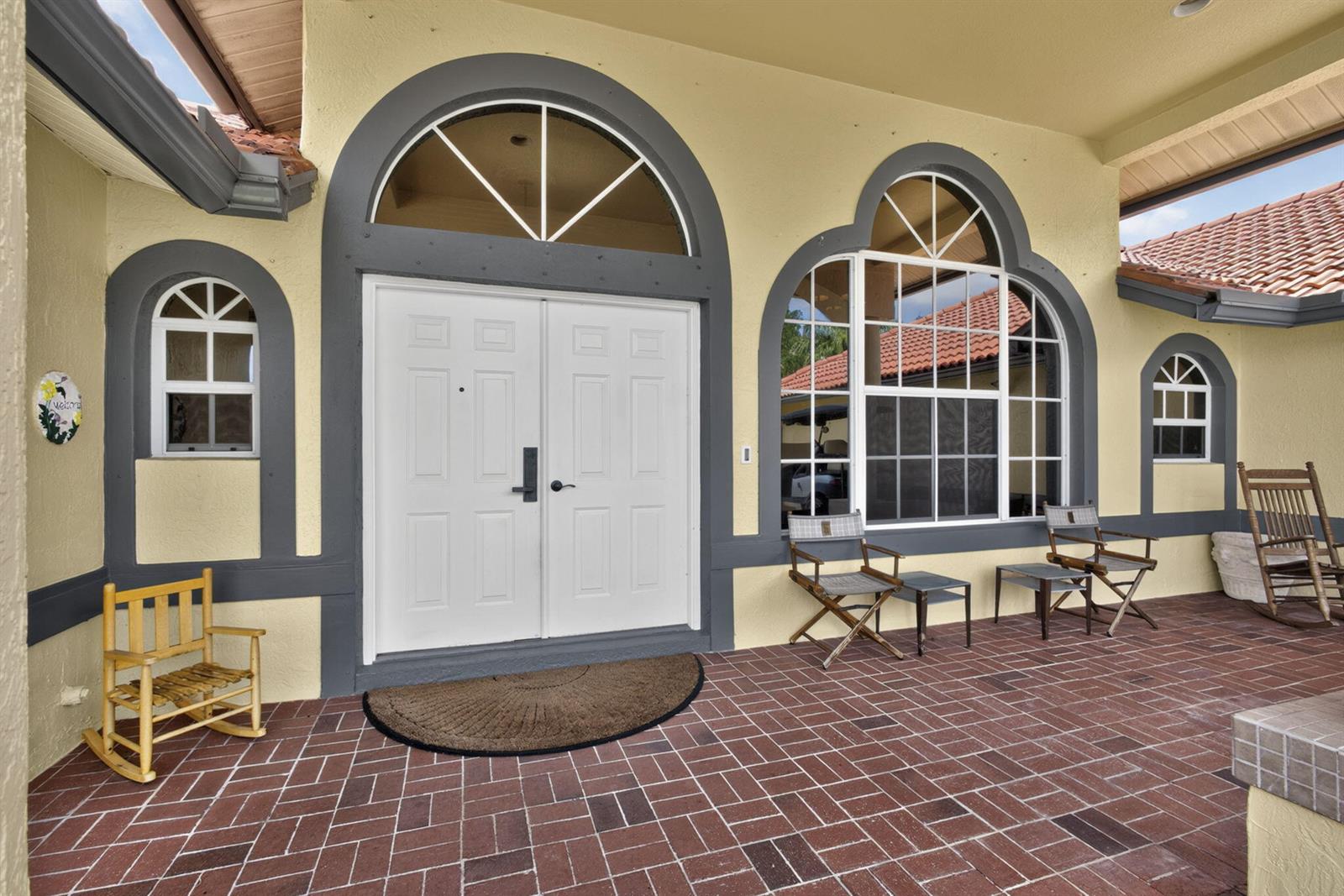 A front porch with red brick pavers features a double door and arched windows — 2564 Deer Run Trail, Loxahatchee FL 33470, LOXAHATCHEE, FL