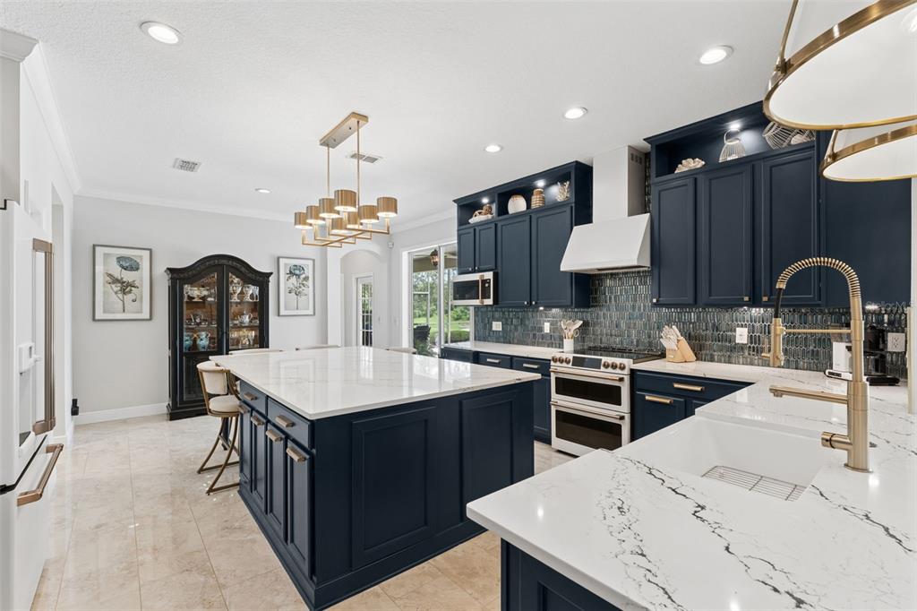 A kitchen with dark blue cabinets, a large white quartz island, and gold hardware — 626 ENGLISH LAKE DRIVE, WINTER GARDEN, FL
