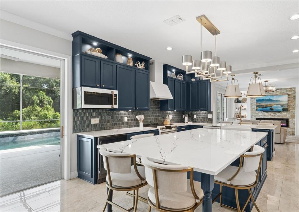 A kitchen features navy blue cabinetry, a large white quartz island, and a glass sliding door — 626 ENGLISH LAKE DRIVE, WINTER GARDEN, FL