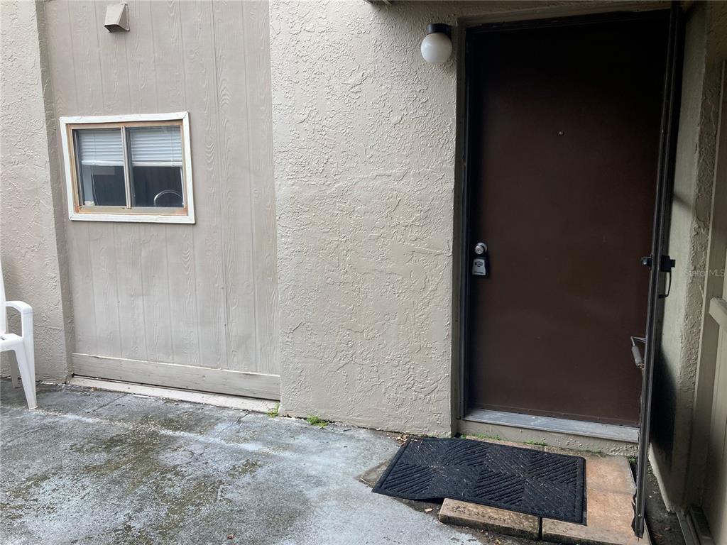 A brown door and a window are set into the beige exterior wall of a building — 8014 PEACH DRIVE UNIT 99, TAMPA, FL