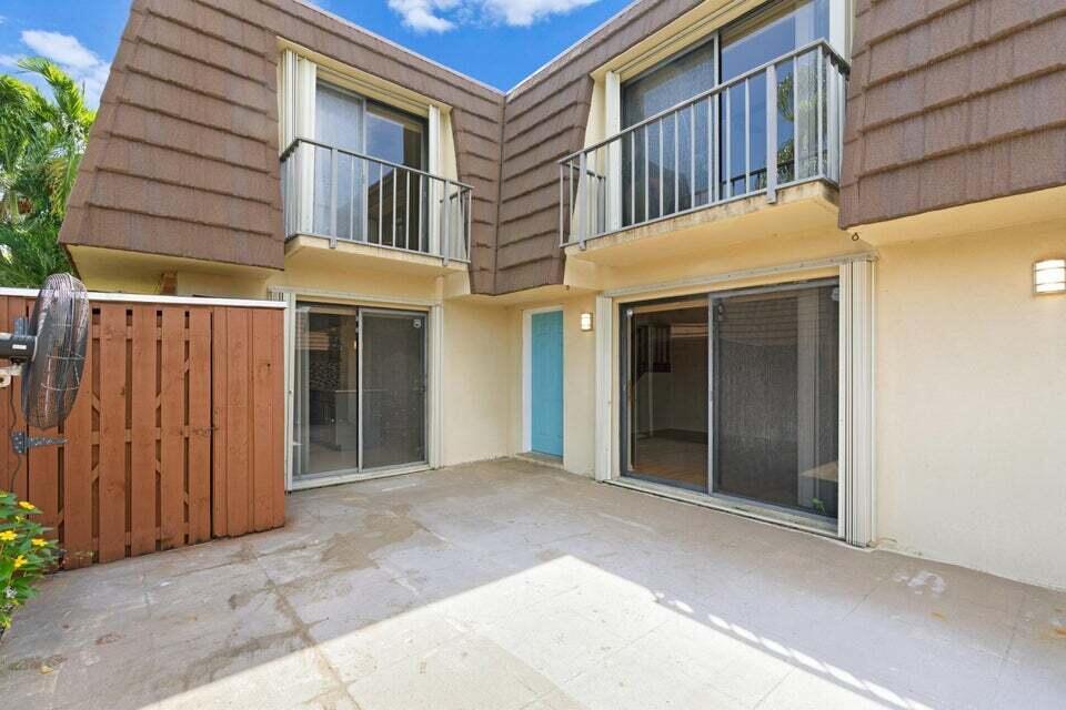 A concrete patio sits in front of a two-story townhouse with sliding glass doors — 3960 August Drive, Lake Worth FL 33461, LAKE WORTH, FL