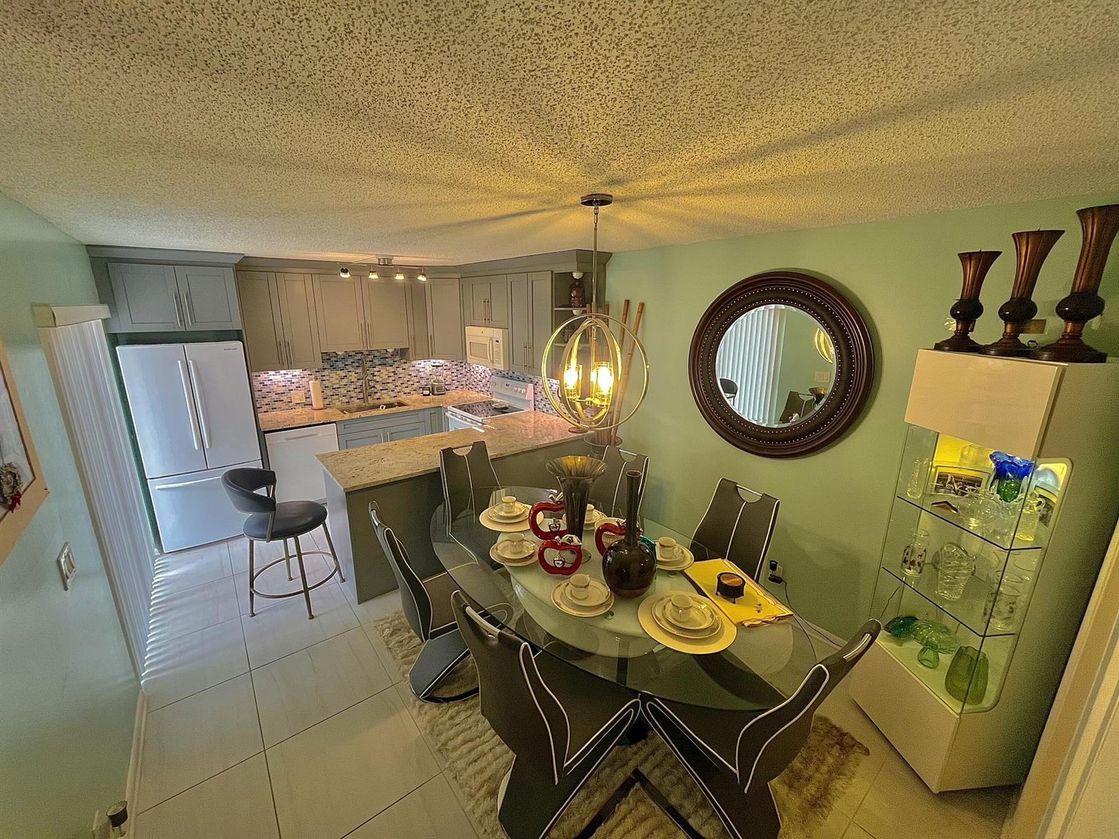 A dining area with a glass table and chairs sits adjacent to a modern kitchen — 3960 August Drive, Lake Worth FL 33461, LAKE WORTH, FL