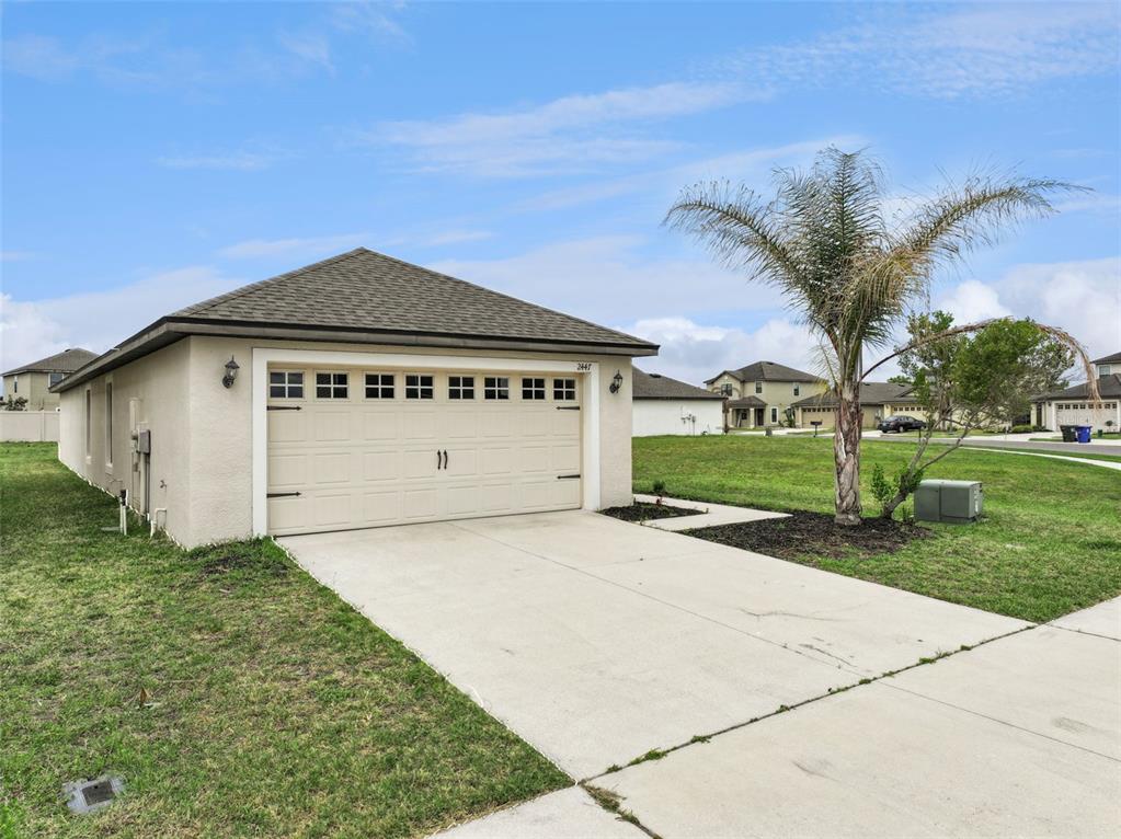 A beige detached garage with a concrete driveway and a palm tree in the yard — 2447 CASPIAN DRIVE, LAKELAND, FL