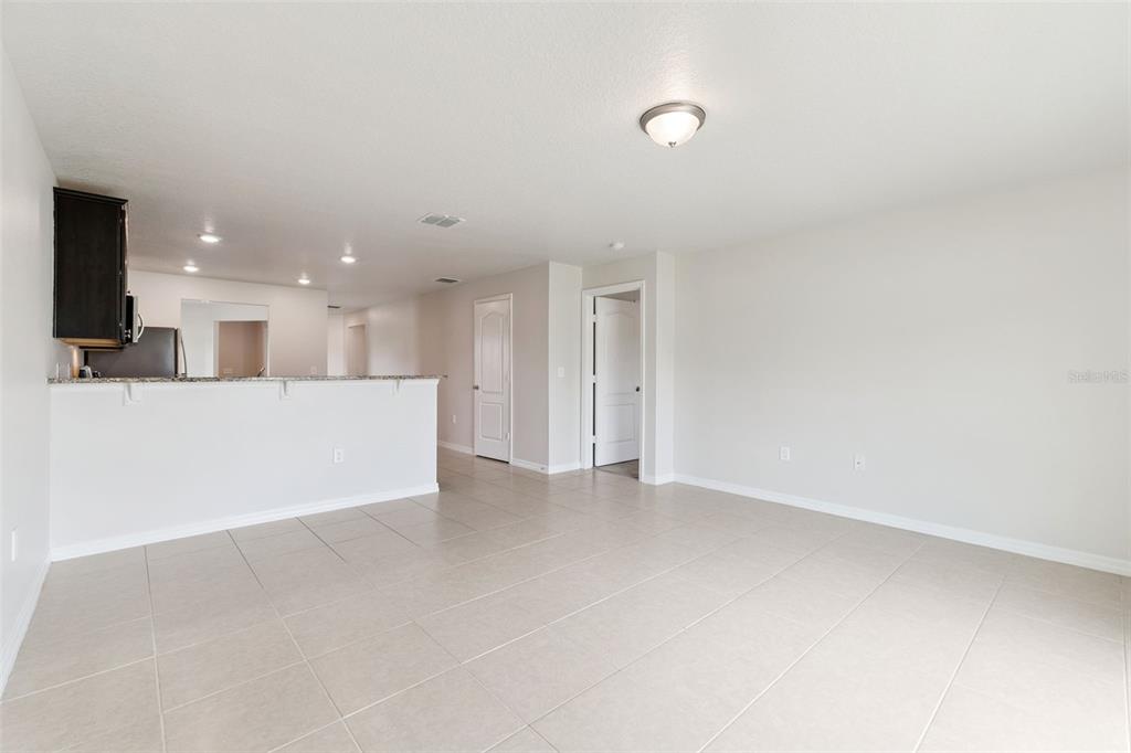 An open-concept living area features light tile flooring, a breakfast bar, and white walls — 2447 CASPIAN DRIVE, LAKELAND, FL