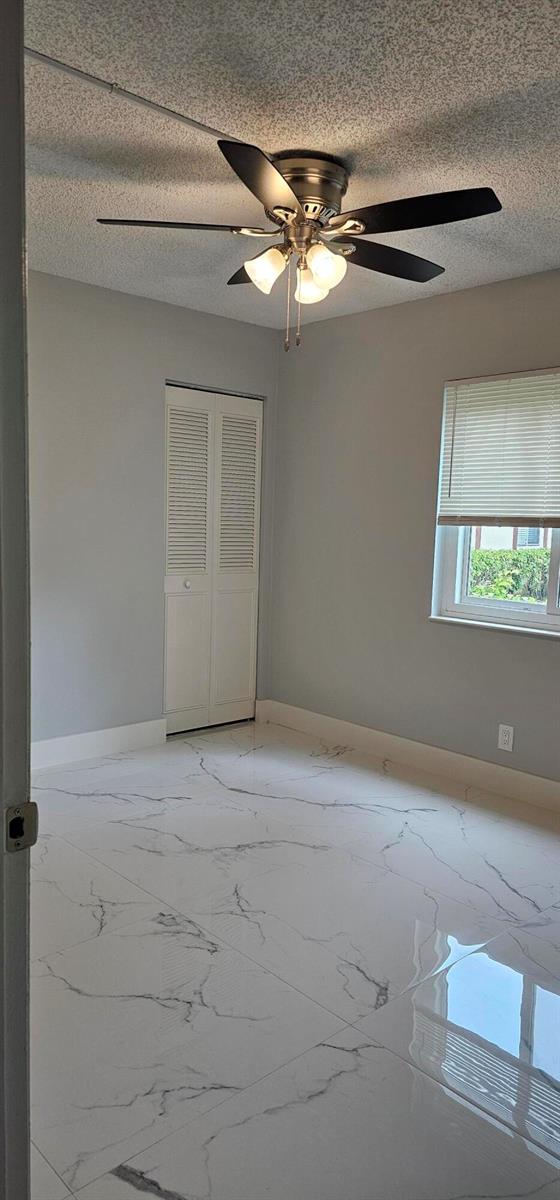 An empty bedroom features light gray walls, white marble-look tile flooring, and a ceiling fan — 4991 Sable Pine Circle # B1, West Palm Beach FL 33417, WEST PALM BEACH, FL
