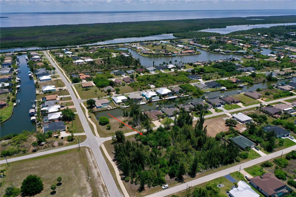 An aerial view shows a vacant, wooded residential lot situated along a canal — 8409 ANTWERP CIRCLE, PORT CHARLOTTE, FL