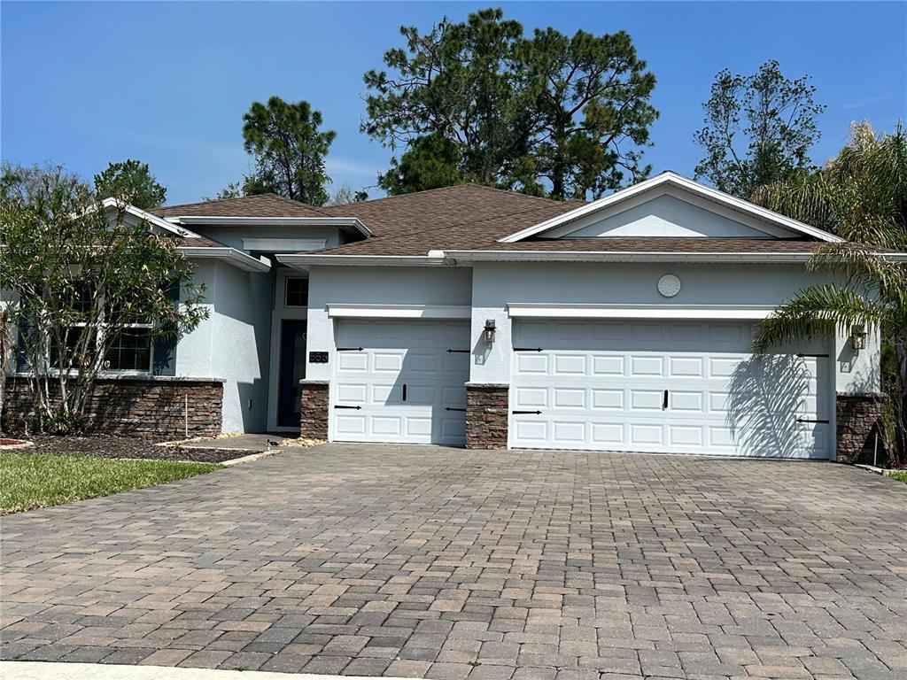 A single-story house with a three-car garage, stone accents, and a paved driveway — 556 BRUNSWICK DRIVE, DAVENPORT, FL