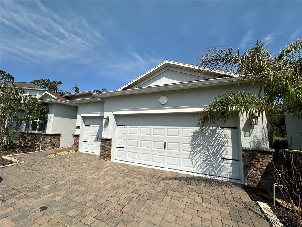 The exterior of a house features a three-car garage, stone accents, and a paved driveway — 556 BRUNSWICK DRIVE, DAVENPORT, FL