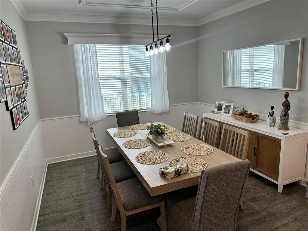 A dining room features a wooden table with six chairs, a sideboard, and wall paneling — 556 BRUNSWICK DRIVE, DAVENPORT, FL