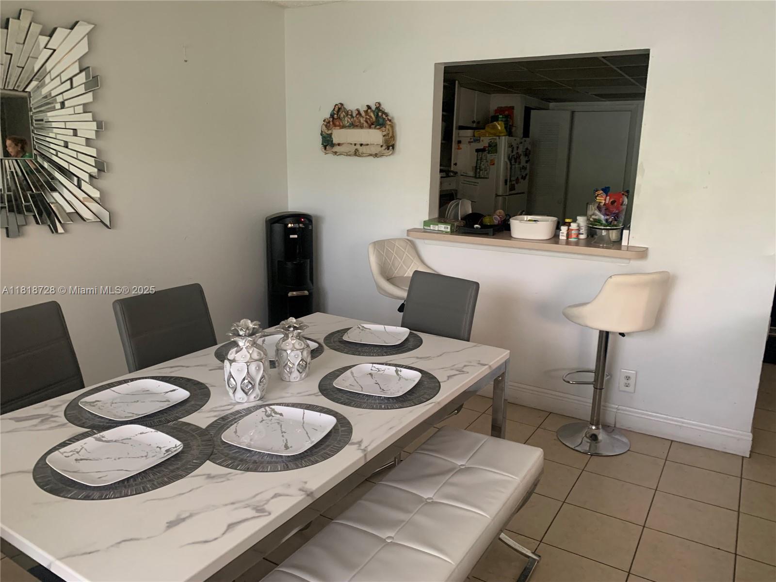 A dining area features a marble-topped table, grey chairs, a white bench, and a breakfast bar — 17911 NW 68th Ave # O104, Hialeah FL 33015, HIALEAH, FL