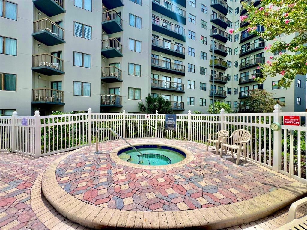 A circular hot tub sits on a paved patio in front of a multi-story apartment building — 6165 CARRIER DRIVE UNIT 3311, ORLANDO, FL