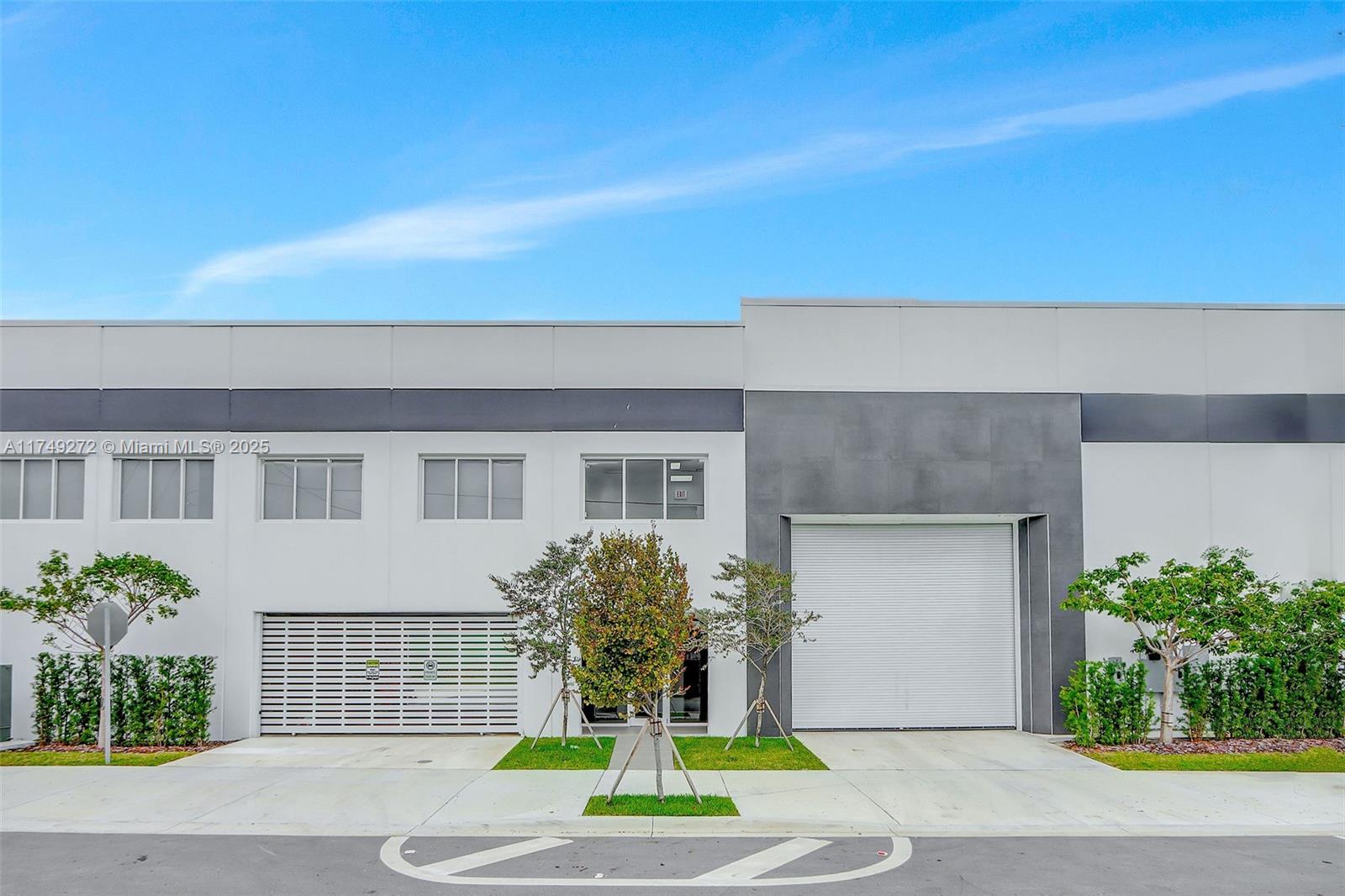 The exterior of a modern industrial building features a roll-up door and a slatted gate — 235 NE 67th St # 3, Miami FL 33138, MIAMI, FL