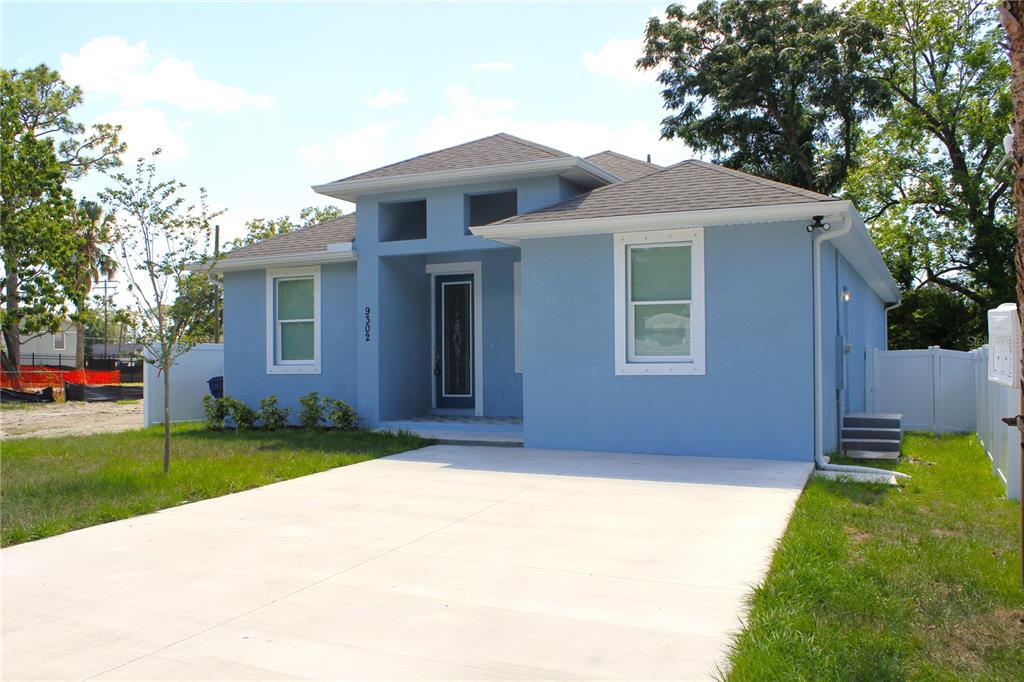 A light blue single-story house with a concrete driveway and a white vinyl fence — 9302 N 18TH STREET, TAMPA, FL