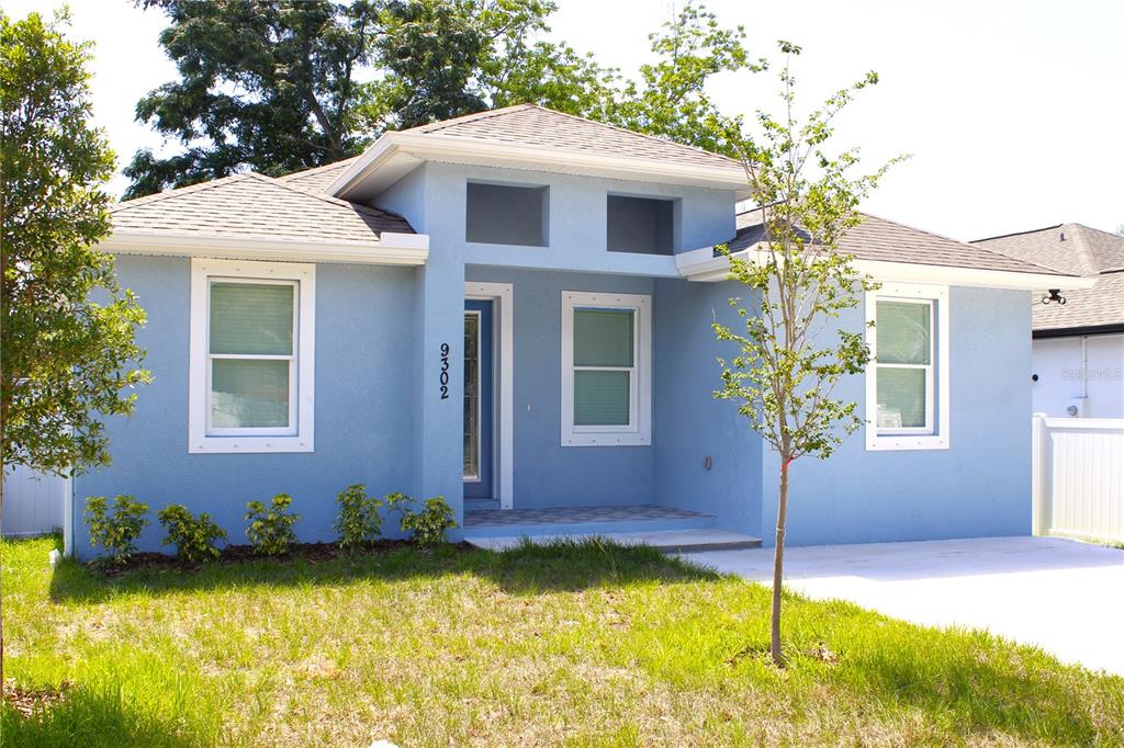 A light blue, single-story house with a hip roof and a covered front entryway — 9302 N 18TH STREET, TAMPA, FL