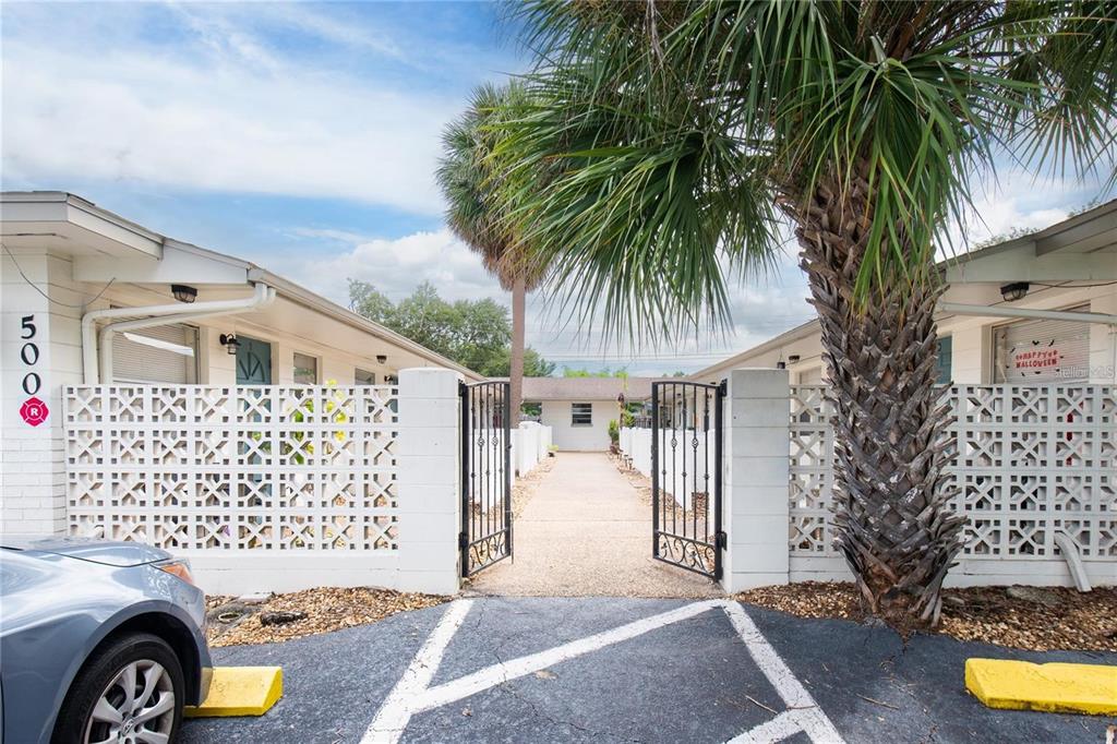 An exterior view of a residential building entrance with a gated walkway and palm tree — 500 75TH AVENUE N, ST PETERSBURG, FL