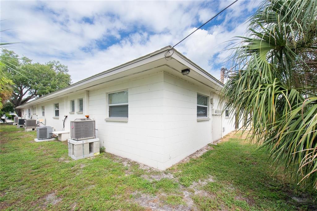 The exterior of a white concrete block building features several air conditioning units and windows — 500 75TH AVENUE N, ST PETERSBURG, FL