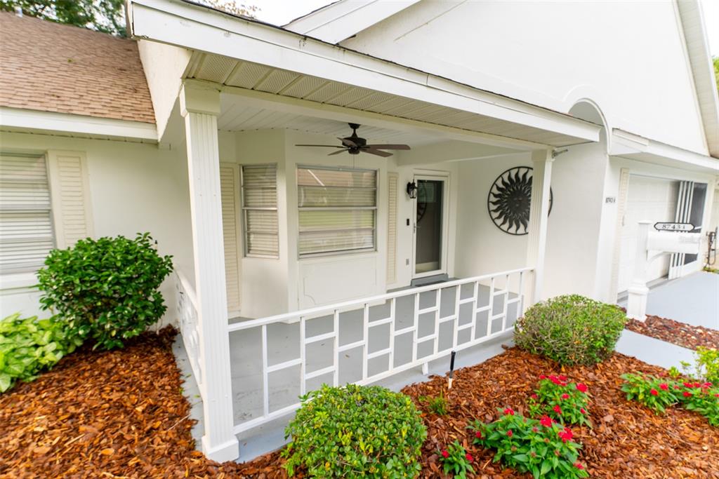 A white house exterior features a covered front porch with a ceiling fan and railing — 8743 SW 90TH LANE UNIT A, OCALA, FL