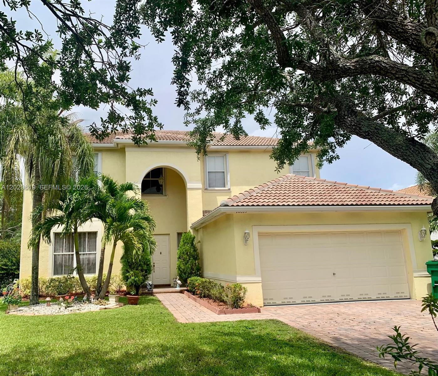A two-story yellow stucco house features a tiled roof, arched entryway, and attached garage — 18815 SW 29th St, Miramar FL 33029, MIRAMAR, FL