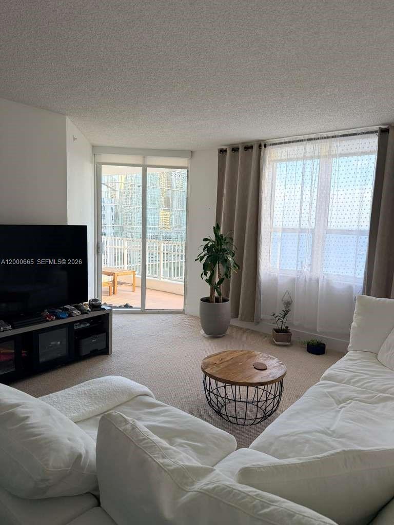 A living room features a white sectional sofa, a round coffee table, and a balcony — 701 Brickell Key Blvd # 1501, Miami FL 33131, MIAMI, FL