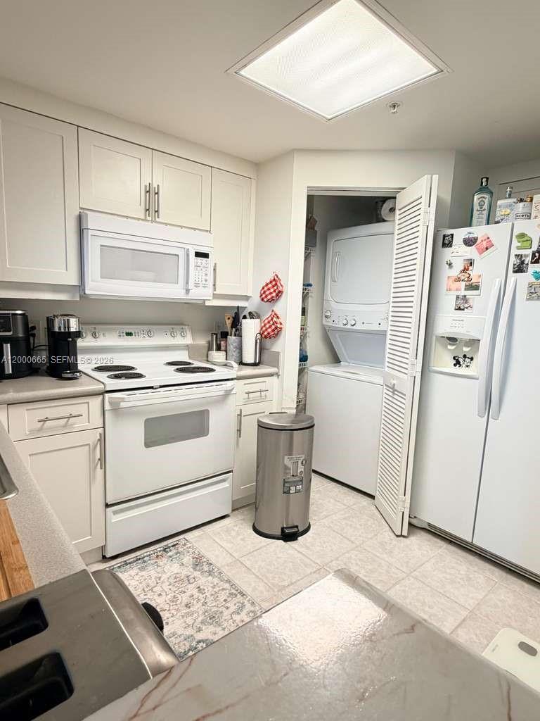A kitchen features white cabinetry, white appliances, a laundry closet, and light-colored tile flooring — 701 Brickell Key Blvd # 1501, Miami FL 33131, MIAMI, FL