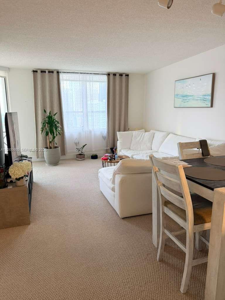 A living room features a white sectional sofa, a dining set, and beige carpeting — 701 Brickell Key Blvd # 1501, Miami FL 33131, MIAMI, FL