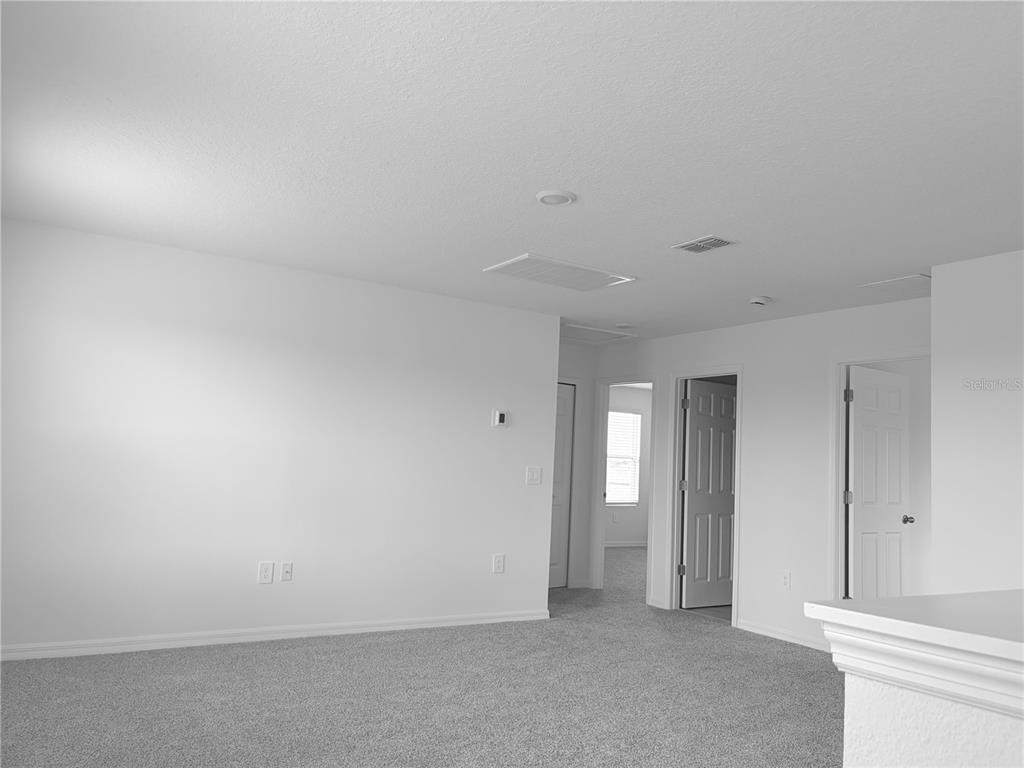 A carpeted room with white walls, two doorways, and a window in the background — 3213 VICEROY COURT, POINCIANA, FL