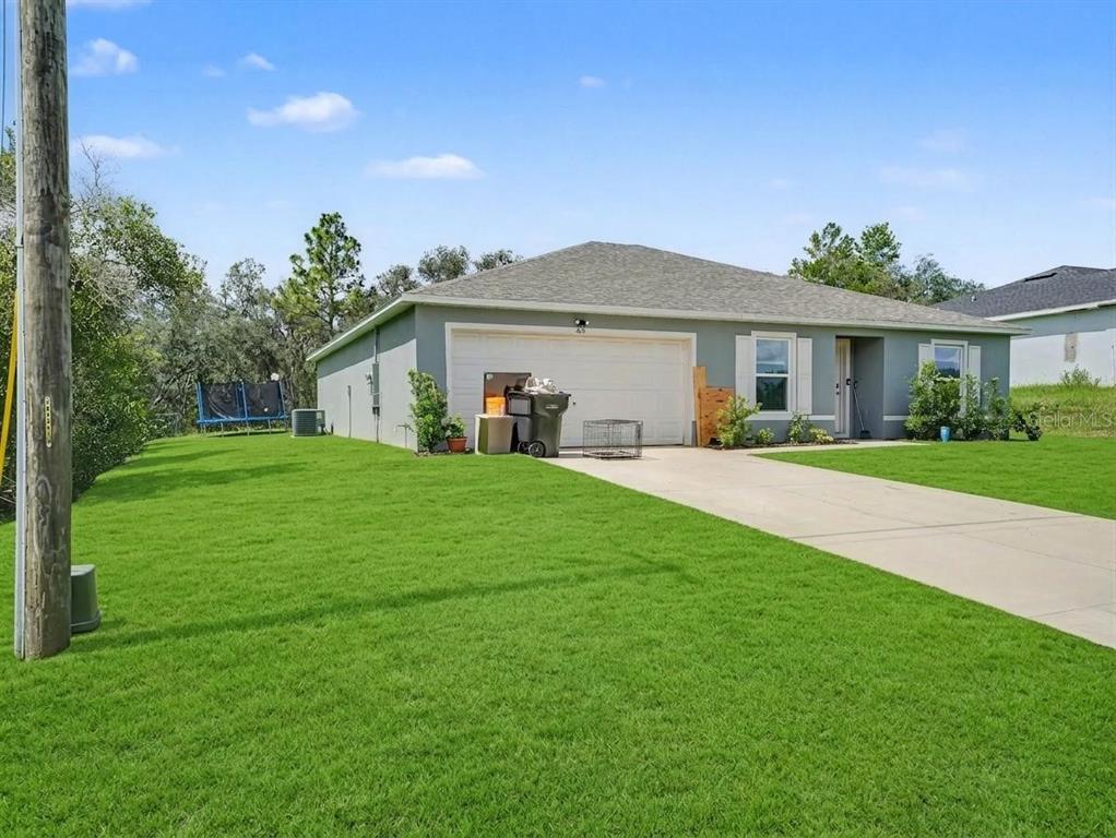 A single-story house with a gray exterior, a two-car garage, and a large front lawn — 305 BOWFIN DRIVE, KISSIMMEE, FL