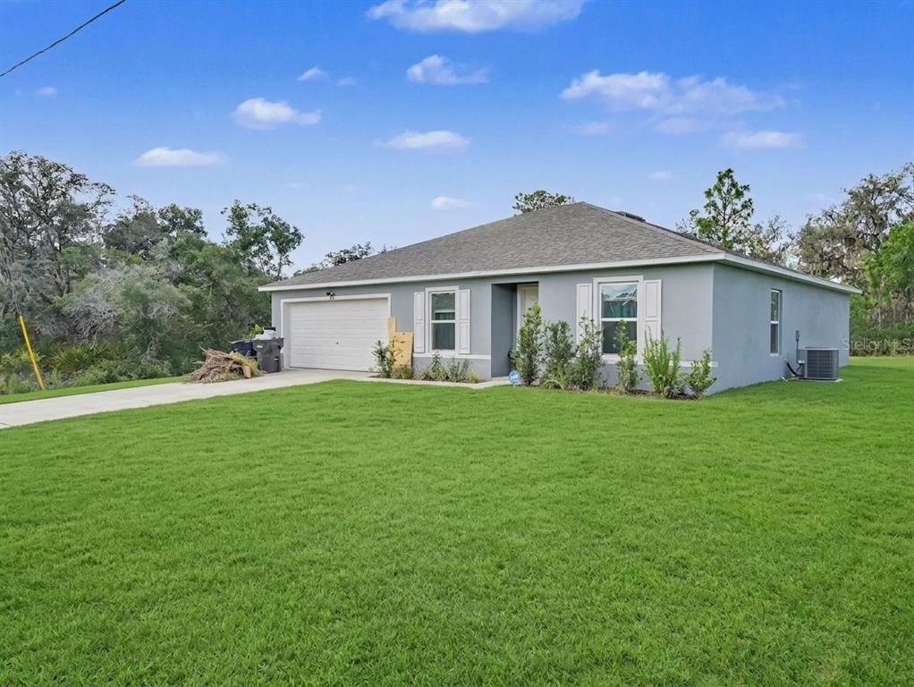 A single-story gray house with a two-car garage sits on a large green lawn — 305 BOWFIN DRIVE, KISSIMMEE, FL