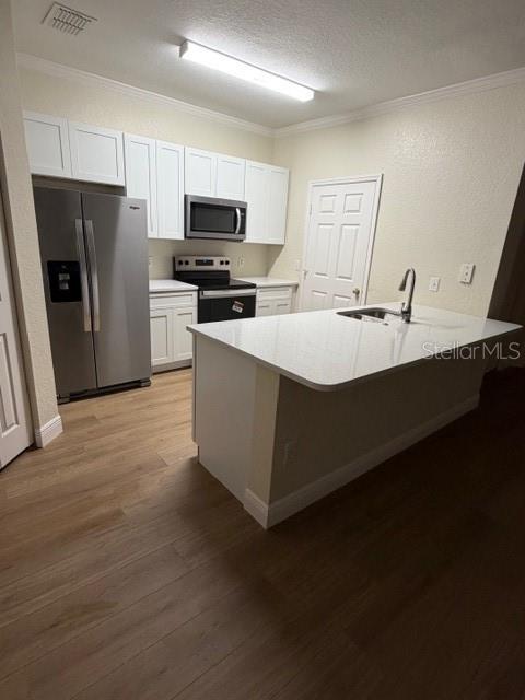 A kitchen features white cabinets, stainless steel appliances, a center island, and light wood flooring — 3707 CONROY ROAD UNIT 1712, ORLANDO, FL
