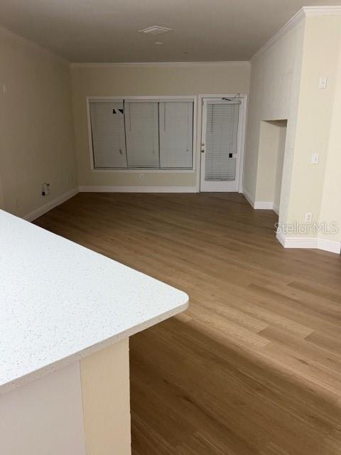 An empty living room features light wood-look flooring, white walls, and a glass-paneled door — 3707 CONROY ROAD UNIT 1712, ORLANDO, FL
