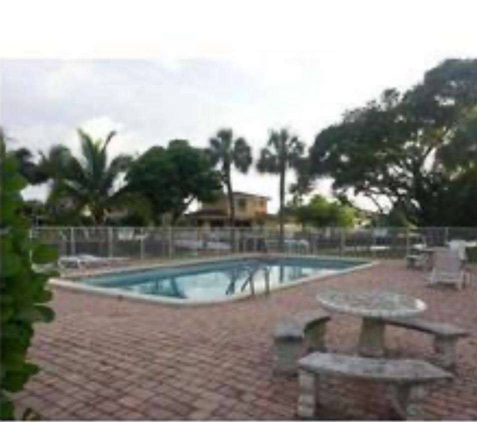 A rectangular swimming pool sits on a brick patio with a stone picnic table — 151 SE 6th Avenue # 12, Pompano Beach FL 33060, POMPANO BEACH, FL